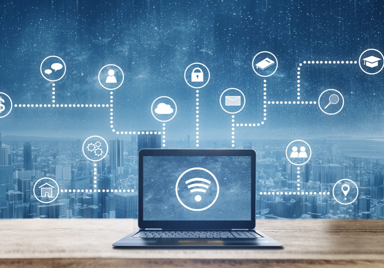 Computer laptop on wooden desk with wireless and application programming and social media icons. Internet networking and wireless technology